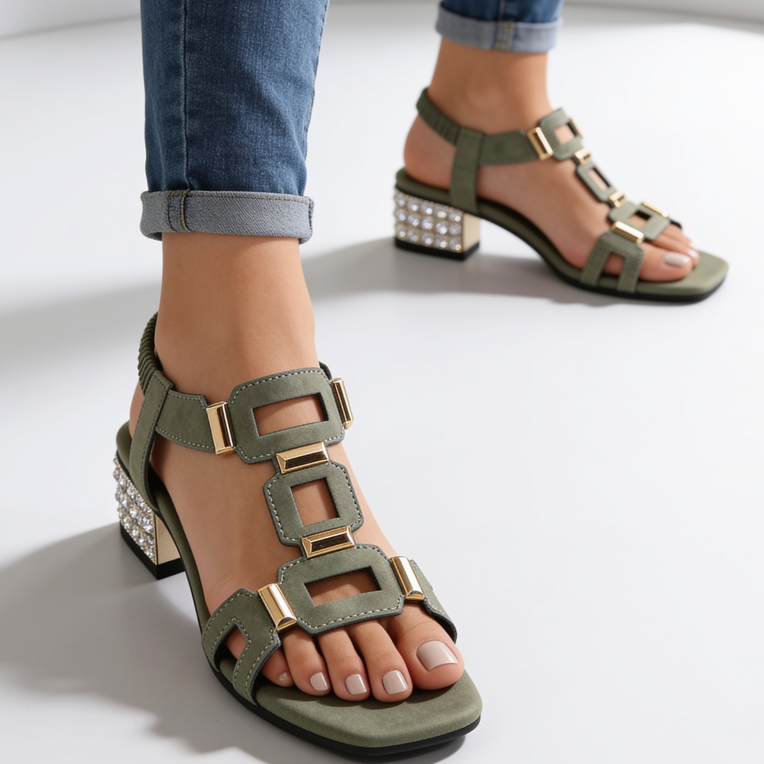 Green strappy sandals on feet with jeweled block heel and gold buckle accents