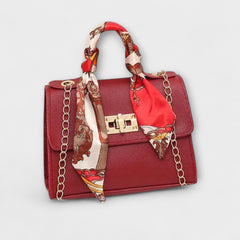 Burgundy handbag with gold clasp, chain strap, and red patterned scarf handle