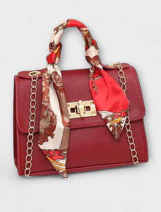 Burgundy handbag with gold clasp, chain strap, and red patterned scarf handle