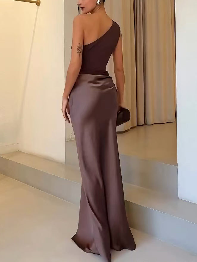 One-shoulder satin maxi dress in dark brown with draped side detail and floor-length fit.