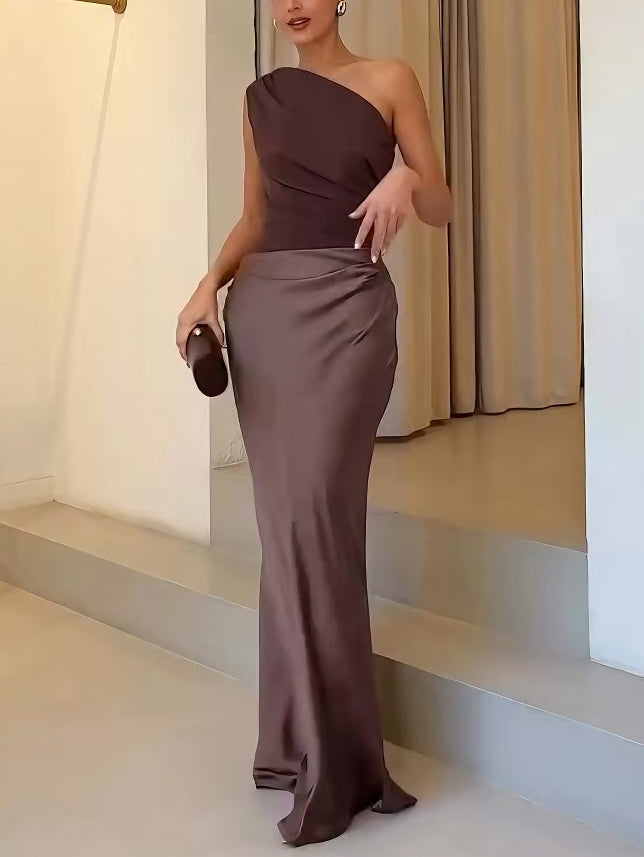 One-shoulder pleated satin maxi dress in dark brown with ruched waist and long fitted hem.