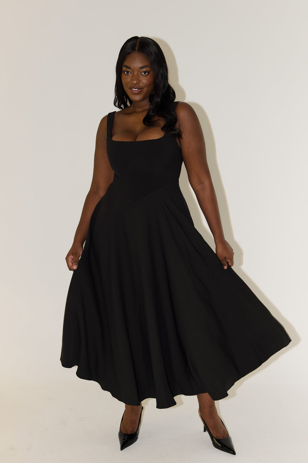 Black sleeveless midi flow dress with square neckline and full pleated skirt