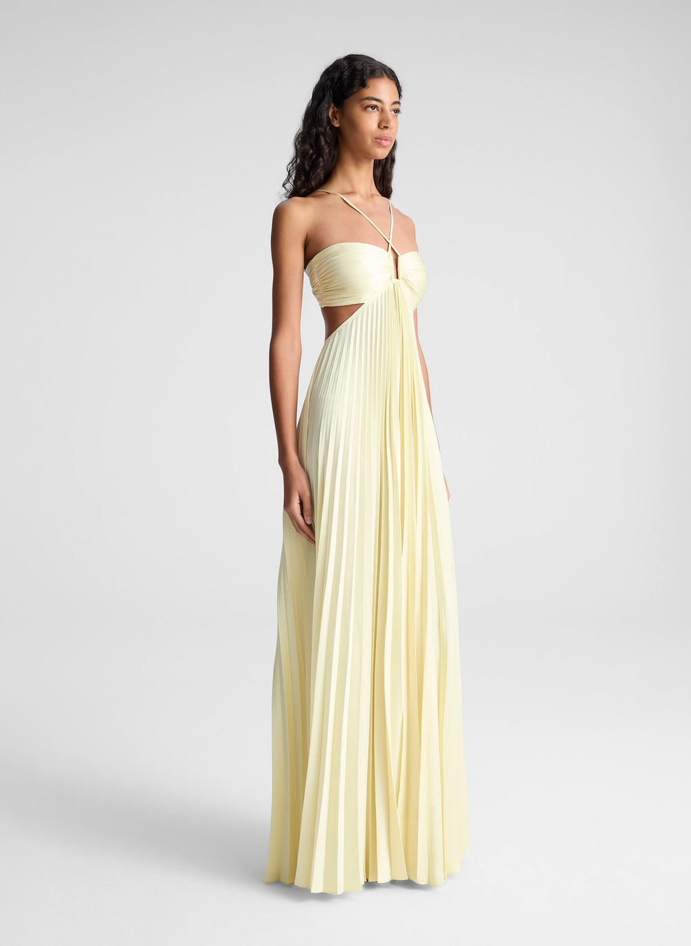 Pleated cut-out gown with pale yellow bodice, spaghetti straps, and floor-length skirt