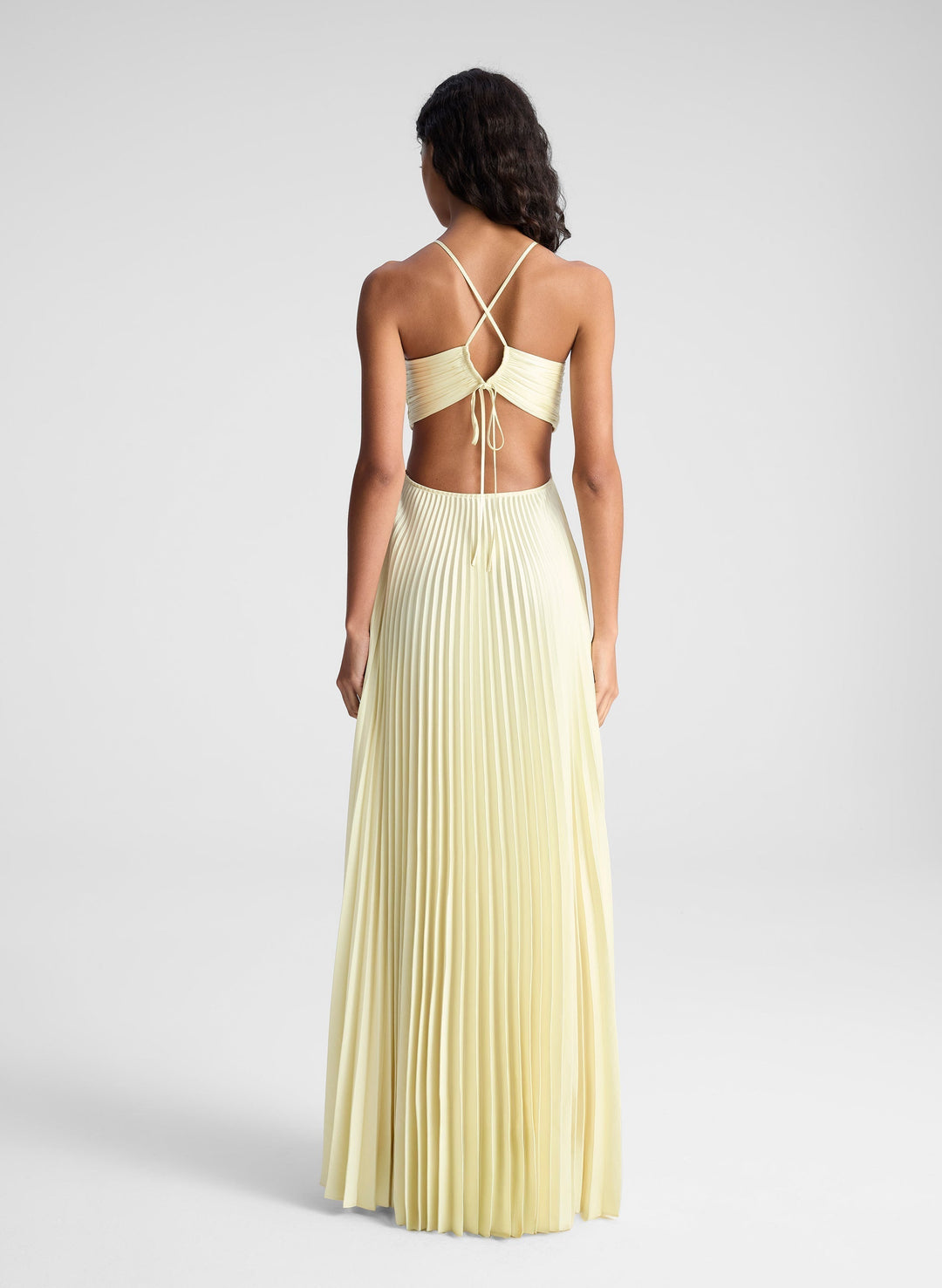 Back view of pale yellow pleated cut-out gown with crisscross straps and open back
