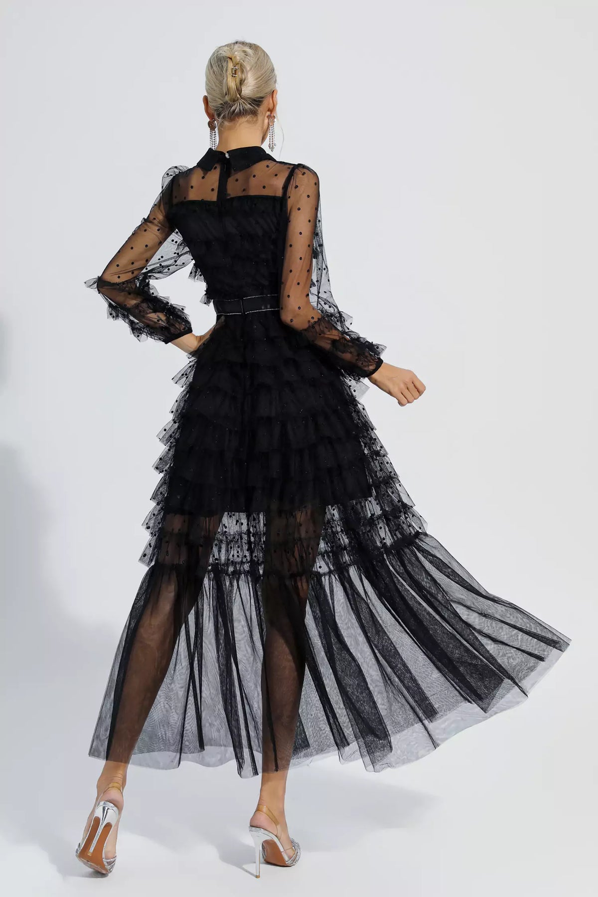 Black maxi dress viewed from back with tiered tulle skirt and sheer polka-dot sleeves