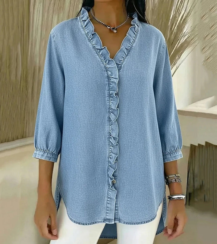 Light blue denim blouse with ruffled V-neck and button-front placket, three-quarter sleeves