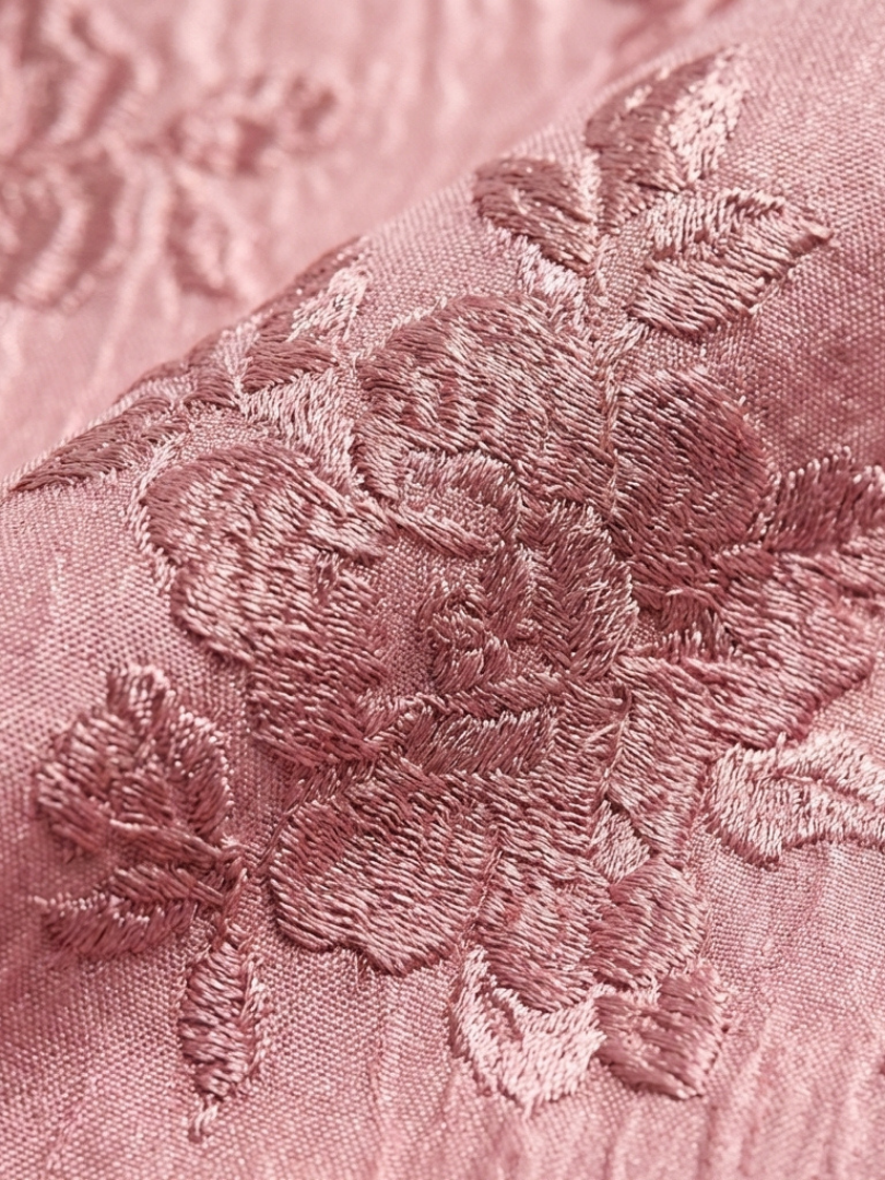 Close-up of pink floral textured fabric with embroidered pattern