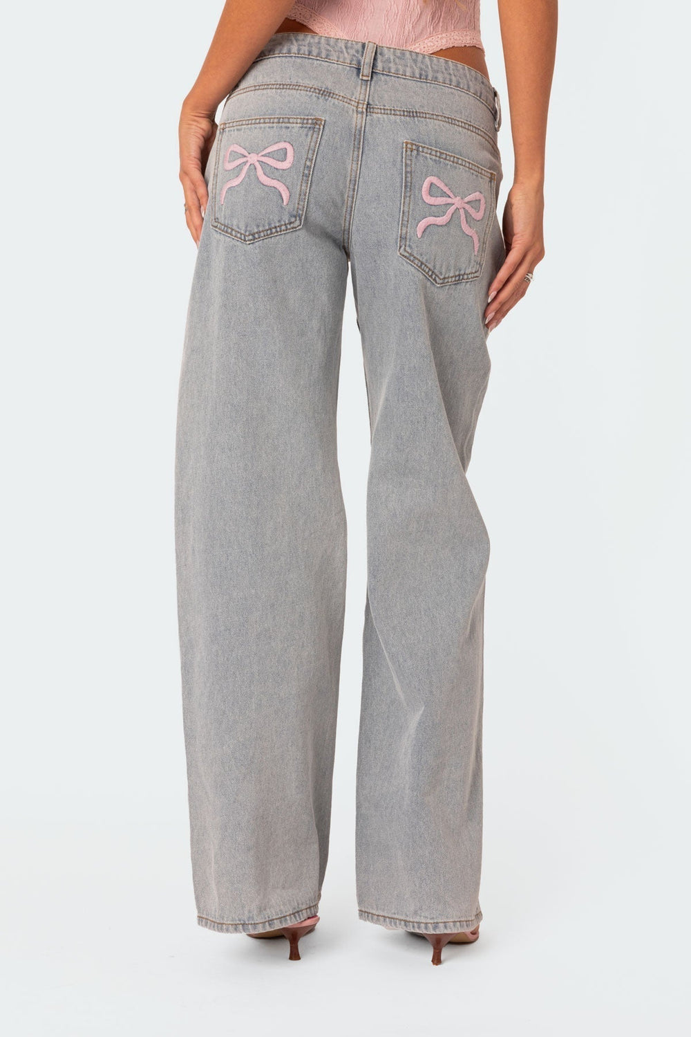 Light gray denim jeans with pink bow-embroidered back pockets and belt loops