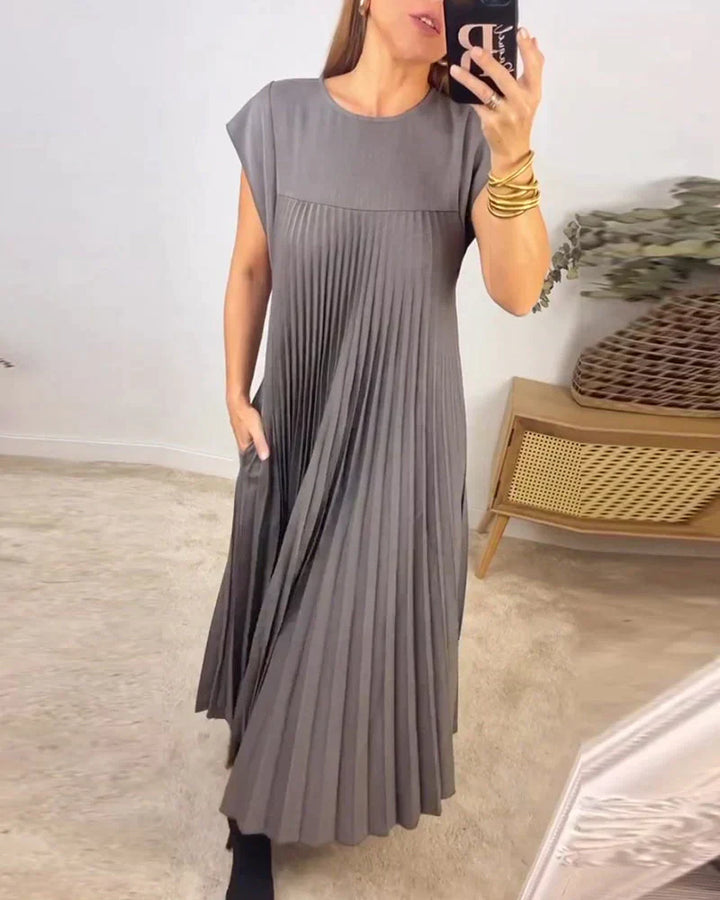 Gray sleeveless pleated maxi dress with round neck and flowing pleat skirt.
