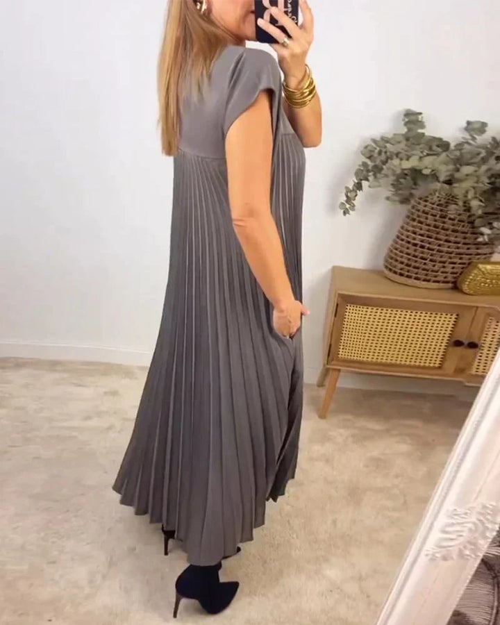 Gray sleeveless pleated maxi dress with round neck and vertical pleats, side view.