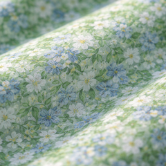 Light green floral fabric close-up with small white daisies and blue accents