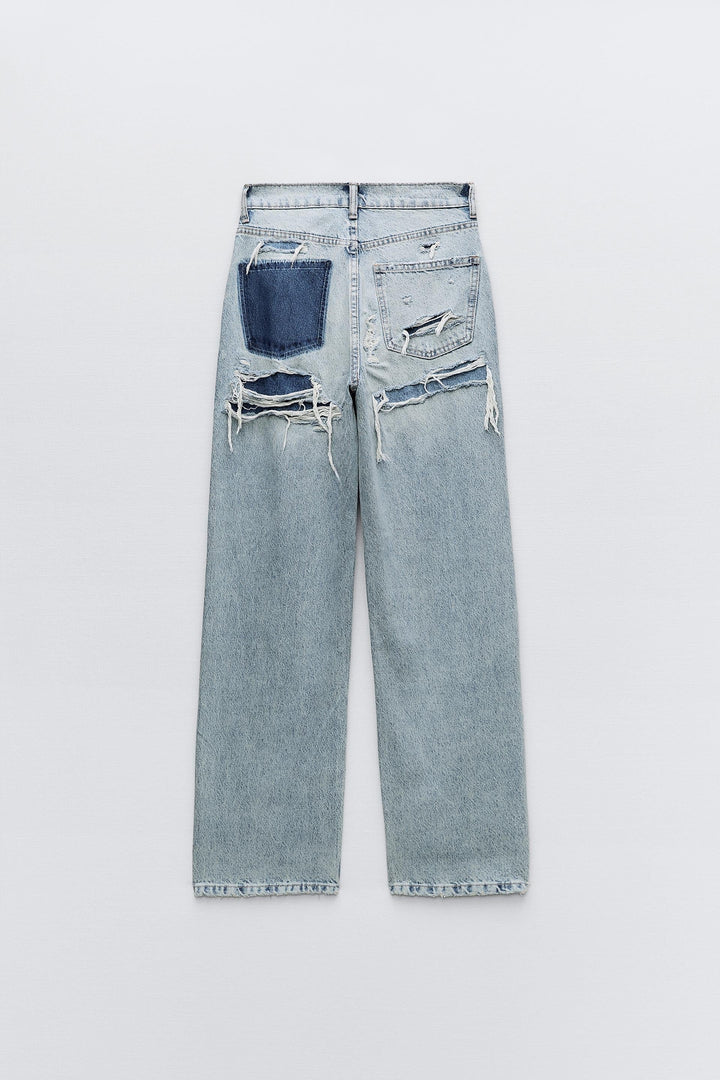 Light wash distressed wide-leg jeans with ripped pockets and frayed hems, flat lay