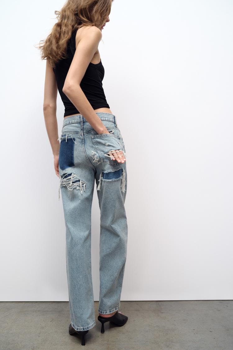 Light wash distressed denim jeans with large ripped back pockets and whiskered seams