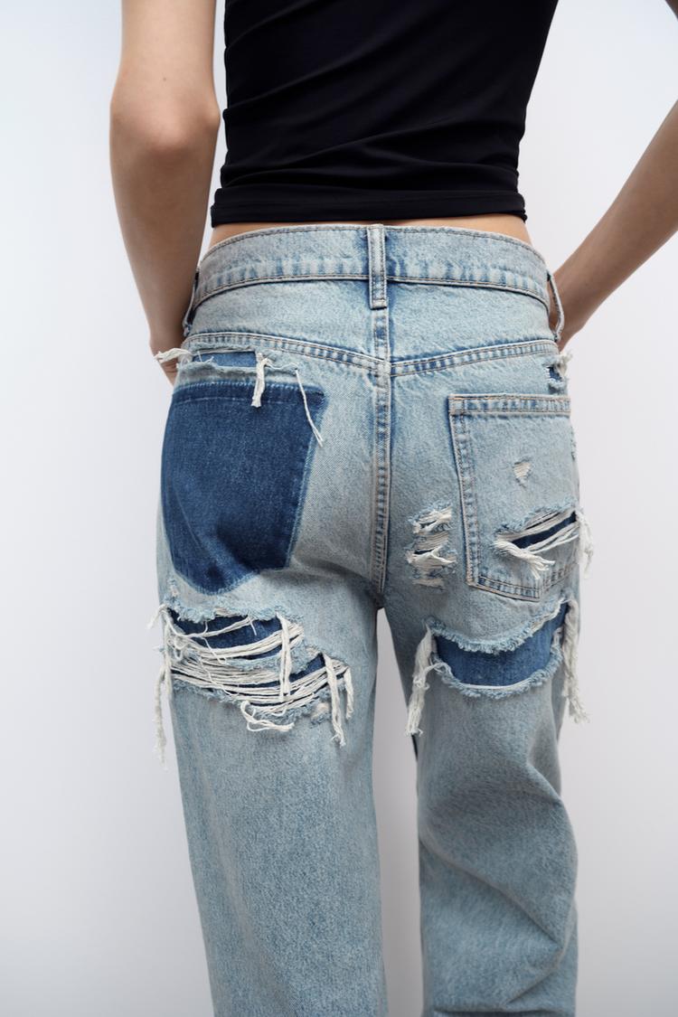Light wash distressed denim jeans with ripped back pockets and frayed leg openings