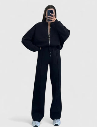 Zip-up sweater and drawstring pants set in black with hooded look and drawstring waist.