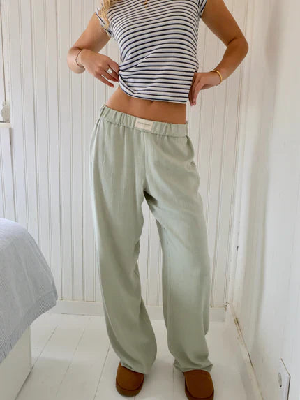 Light olive-green lounge trousers with elastic waistband, loose straight-leg fit