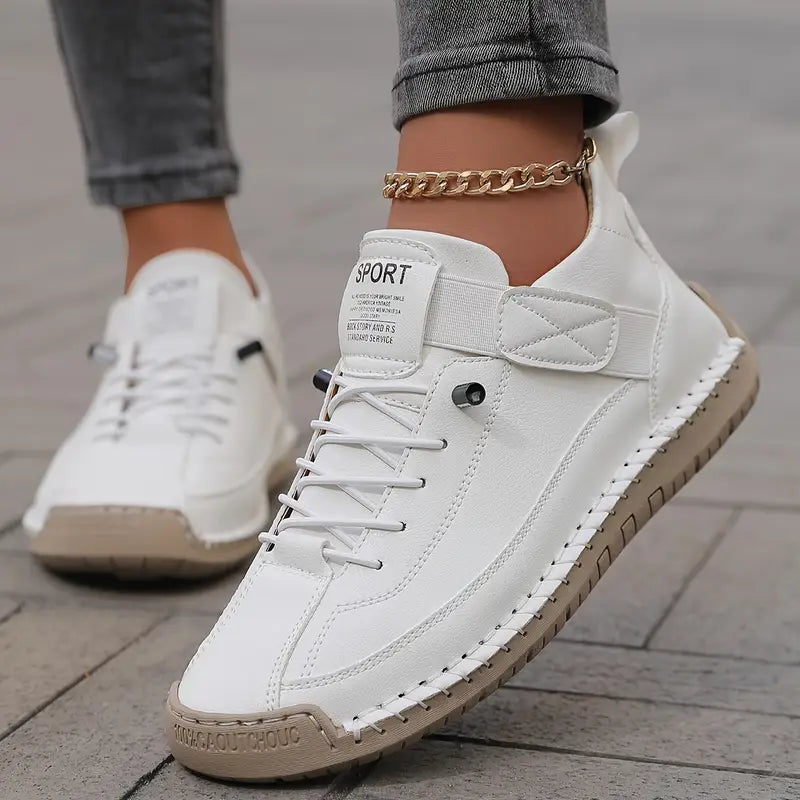 White lace-up sneaker with quilted side strap and tan outsole, shown on a foot