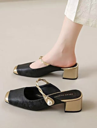 Black genuine leather mules with block heel, chain strap, and round pearl embellishment.