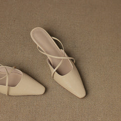 Pair of beige leather mules with crisscross straps and pointed toe, low heel