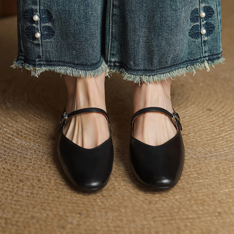 Black genuine leather mules with slip-on strap and buckle detail, worn with denim
