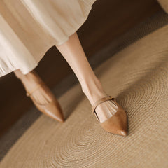 Tan leather mules on a person’s foot with pointed toe and ankle strap