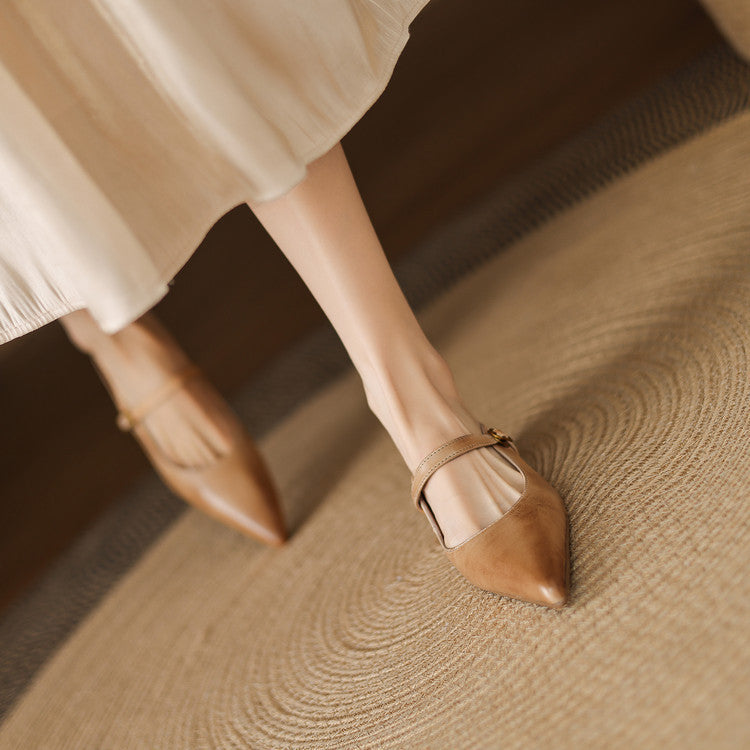 Tan leather mules on a person’s foot with pointed toe and ankle strap