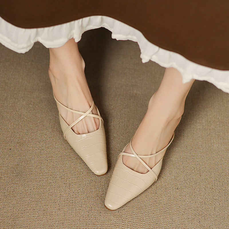 Beige leather mules on model feet, crisscross straps, pointed toe, low heel