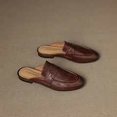 Brown leather mules set on a textured surface, square-toe slip-on with strap