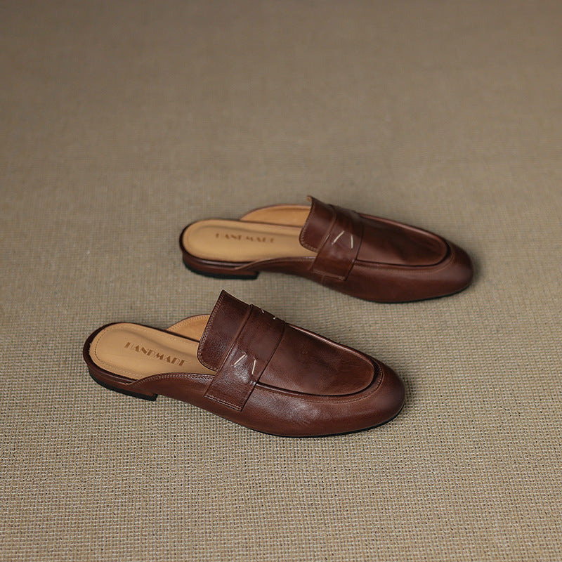 Brown leather mules set on a textured surface, square-toe slip-on with strap
