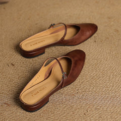 Brown genuine leather mules shown from side: cross strap and low stacked heel