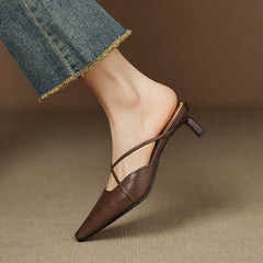 Brown genuine leather mules with crisscross ankle strap and mid heel detail.