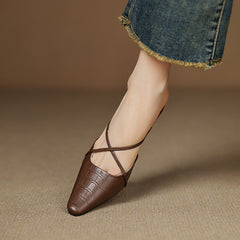 Brown genuine leather mule on foot with crisscross straps and mid block heel.