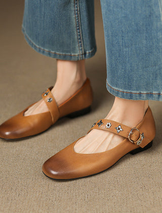 Tan leather flats with buckle strap and star-flower accents, low black sole