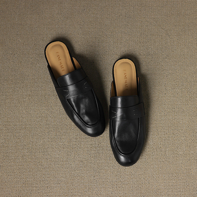 Black genuine leather slip-on mules with strap detail and cushioned rounded toe