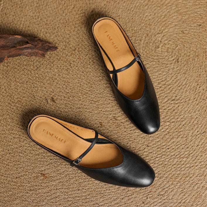 Black leather pointed-toe mules with T-strap and tan footbed