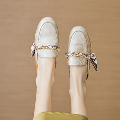 Beige leather mules with gold chain detail and bow, shown from front and back