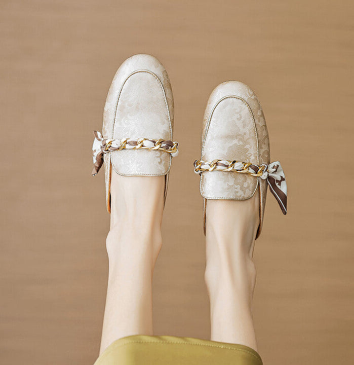 Beige leather mules with gold chain detail and bow, shown from front and back