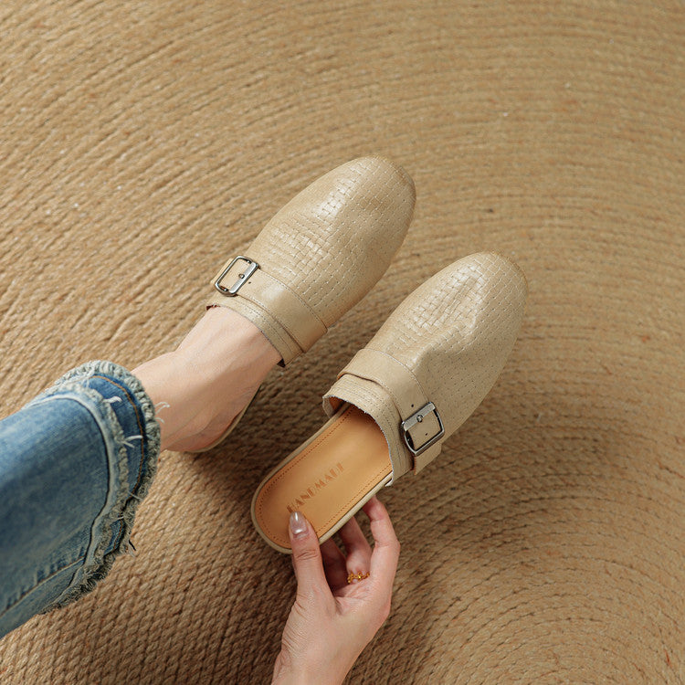 Beige leather mule with buckle strap and flat sole, held in hands
