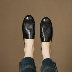 Black genuine leather mules worn with blue jeans, rounded toe slip-on design