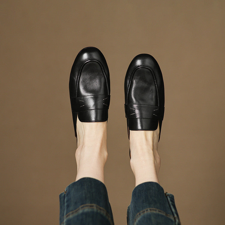 Black genuine leather mules worn with blue jeans, rounded toe slip-on design