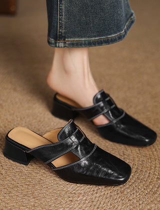 Black leather mule with buckle strap and low block heel worn on foot