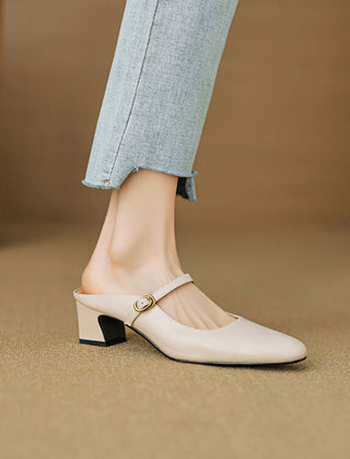 Beige leather mules with low block heel and round toe, worn with light blue jeans.