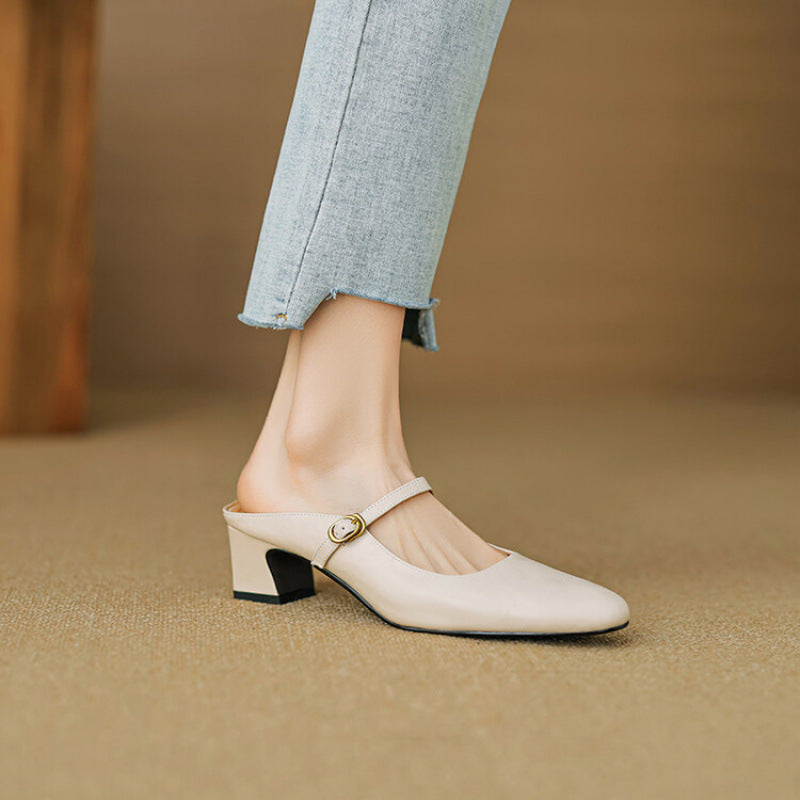Beige leather mules with low block heel and round toe, worn with light blue jeans.