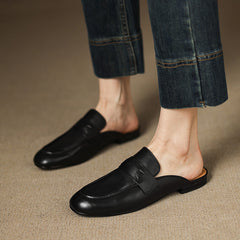 Black leather slip-on mules worn with jeans, rounded toe and stitched vamp