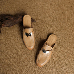 Two tan leather mules with square toe and metallic buckle strap