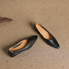 Black leather pointed-toe mules with tan insole lining and slip-on V-cut vamp.