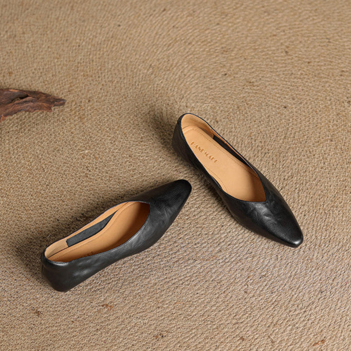 Black leather pointed-toe mules with tan insole lining and slip-on V-cut vamp.