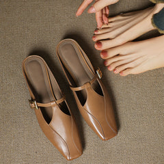 Brown leather mules with open sides, pointed toe, and gold buckle strap, held pair