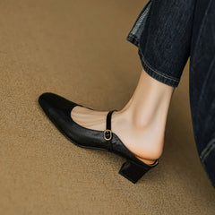 Black leather mule with slip-on design, rounded toe, and buckled strap