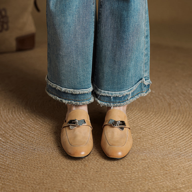 Tan leather mules with square toe and metallic buckle strap on denim jeans